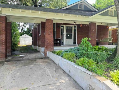 View of front of home featuring brick siding, a shingled roof, concrete driveway, and covered porch