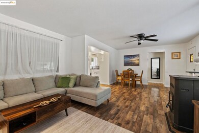 Living room with ceiling fan and dark wood-type flooring