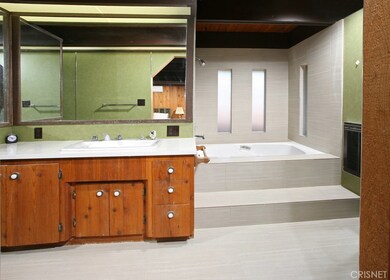 Sumptuous en suite master bathroom with vanity, large dressing mirror, built-in make-up table, soothing step-up tiled soaking tub/shower, privacy windows and tiled floors.