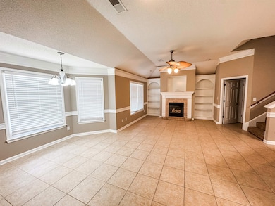 Unfurnished living room with built in features, ceiling fan, light tile patterned floors, a chandelier, and a textured ceiling