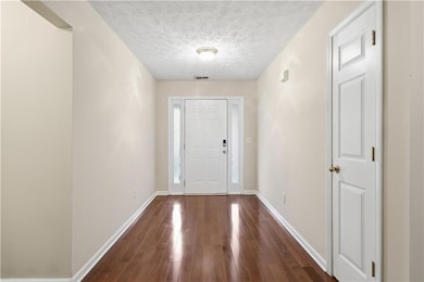 Entrance foyer featuring dark wood-style flooring and a textured ceiling