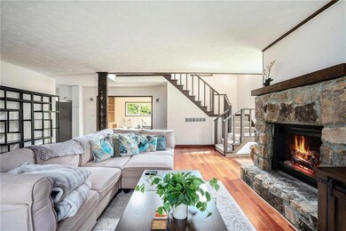 Living room featuring wood finished floors, a fireplace, stairs, and a textured ceiling