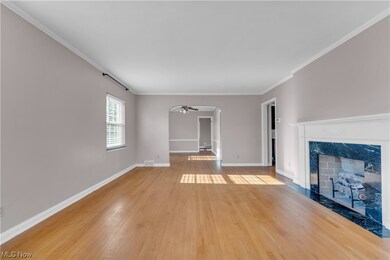 Unfurnished living room with ceiling fan, a fireplace, crown molding, and light hardwood / wood-style floors