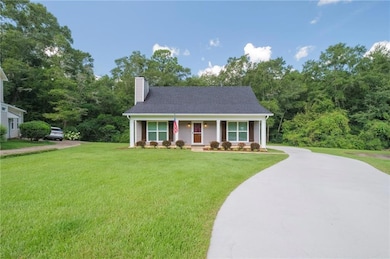 View of front of property with a chimney, driveway, a front lawn, and covered porch