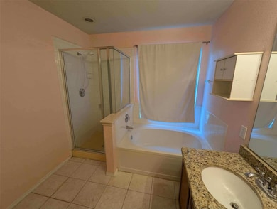 Bathroom with a garden tub, vanity, light tile patterned flooring, and a shower stall