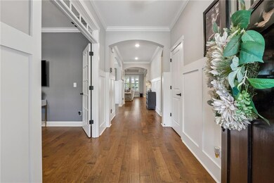 Foyer entrance featuring arched walkways, dark wood finished floors, crown molding, and a decorative wall