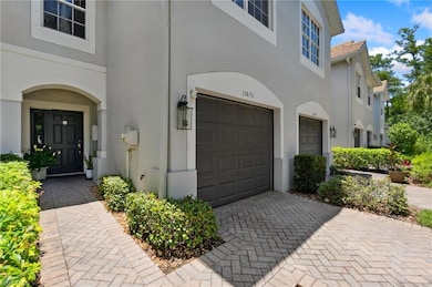 Doorway to property featuring stucco siding, a garage, a tiled roof, and decorative driveway