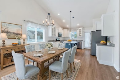 Dining room featuring high vaulted ceiling, a chandelier, recessed lighting, and light wood finished floors