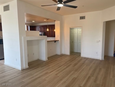 Unfurnished living room featuring a ceiling fan, light wood-style flooring, and baseboards