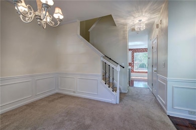 Staircase with a wainscoted wall, carpet flooring,