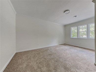 Carpeted spare room with crown molding and baseboards