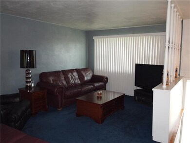 The living room features a large window with verti
