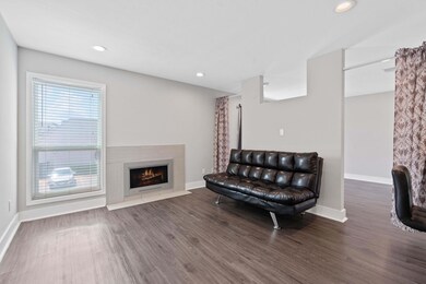 Living area with wood finished floors, a fireplace with flush hearth, and recessed lighting