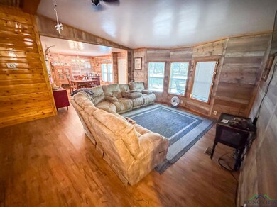 Living room featuring wood walls, wood finished floors, lofted ceiling, and a chandelier