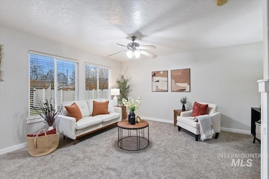 Living area featuring a textured ceiling, light carpet, a ceiling fan, and a fireplace