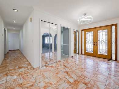 Foyer entrance featuring arched walkways, french doors, a chandelier, light marble finish floors, and recessed lighting