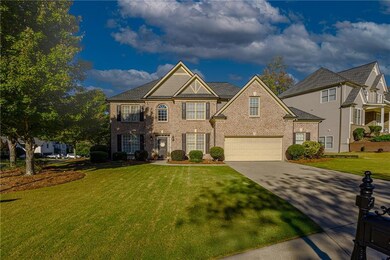 View of front facade featuring a front lawn, concrete driveway, and brick siding