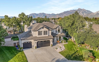 View of front facade with stucco siding, roof with shingles, a front yard, a mountain view, and driveway