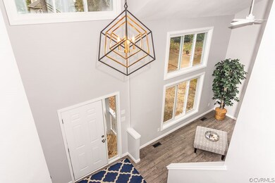 Looking down the foyer stairs to the front door open to the living room. New light.