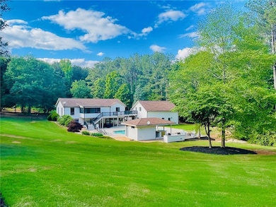 Back of property featuring a lawn, an outdoor structure, stairs, and a deck