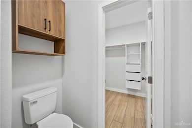 Bathroom featuring toilet, wood finished floors, and baseboards