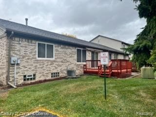 Back of property with a deck, a lawn, and brick siding