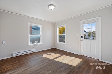 Foyer with a baseboard radiator, dark wood-type flooring, and ornamental molding