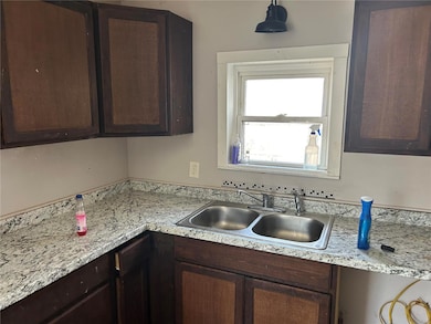 Kitchen with dark brown cabinetry, light countertops, and a sink