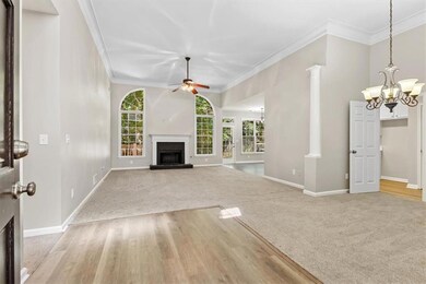Unfurnished living room with a fireplace with raised hearth, ornamental molding, a chandelier, light wood-style flooring, and light colored carpet