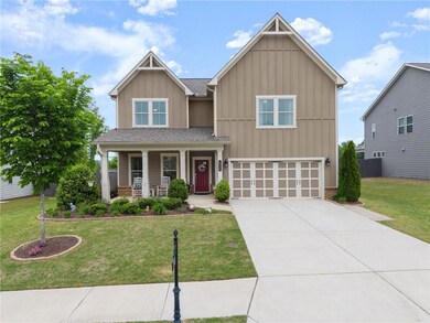 Craftsman house with a garage, a front yard, board