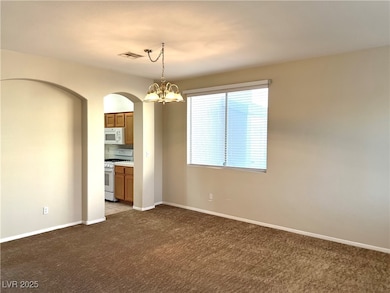 Carpeted spare room featuring arched walkways, an