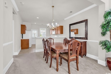 Dining space featuring a chandelier, light colored carpet, ornamental molding, baseboards, and recessed lighting