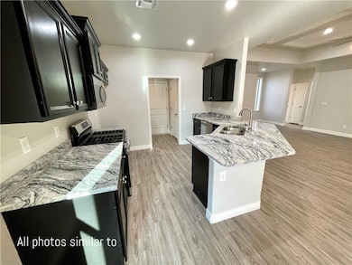Kitchen with a sink, dark cabinets, appliances wit