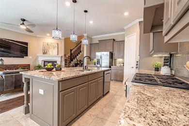 Kitchen featuring open floor plan, ornamental molding, decorative light fixtures, tasteful backsplash, and gray cabinets