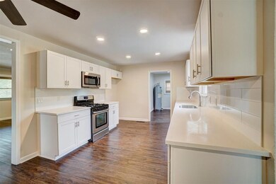 Kitchen with ceiling fan, white cabinets, tasteful