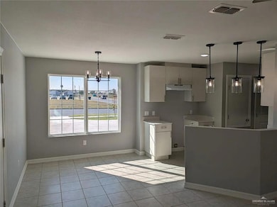 Kitchen featuring light tile patterned flooring, hanging light fixtures, light countertops, and a chandelier