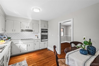 Kitchen with black electric stovetop, light hardwo