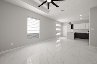 Unfurnished living room with ceiling fan with notable chandelier and sink