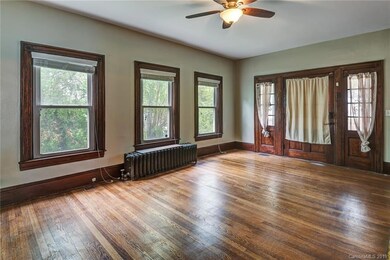Home entry into grand living room, with original hardwoods and partially open concept flowing from living room to family room, to dining room and kitchen.