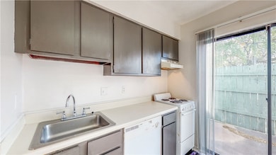 Kitchen featuring gray cabinets, a sink, light cou