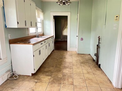 Kitchen with white cabinetry, sink, and light tile