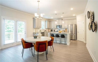 Dining room with ornamental molding, light wood-style flooring, a chandelier, and recessed lighting