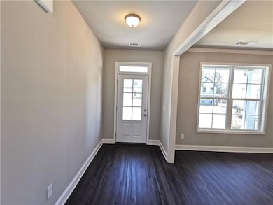 Foyer entrance featuring dark wood-style flooring and crown molding