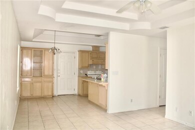 Kitchen featuring a raised ceiling, light brown cabinetry, light tile patterned floors, light countertops, and white range with electric stovetop