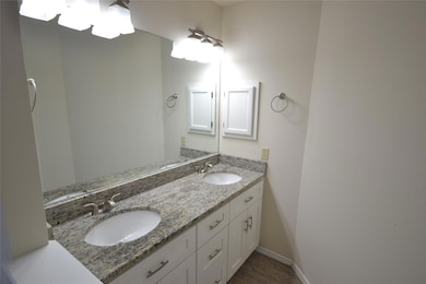 Full bathroom with double vanity and baseboards