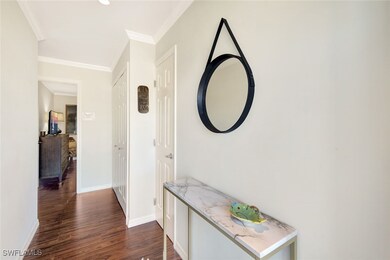 Hall with crown molding and dark wood-type floorin