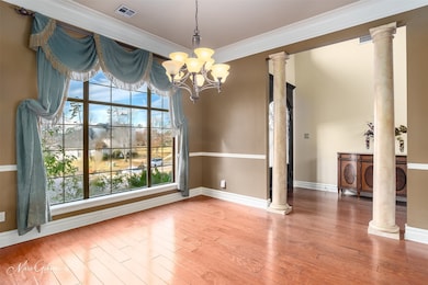 Unfurnished dining area with wood-type flooring, crown molding, a chandelier, and decorative columns