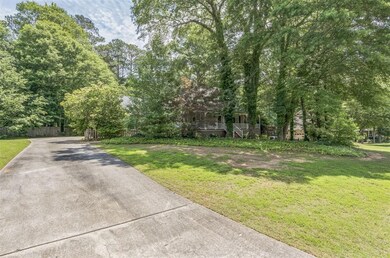 View of concrete driveway featuring view of wooded area