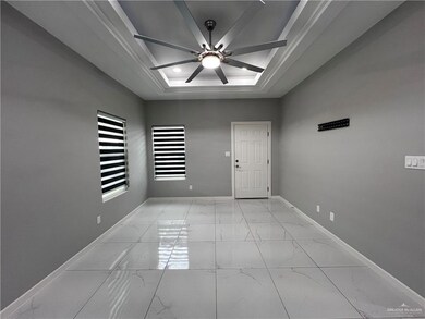 Unfurnished room featuring light marble finish flooring, ceiling fan, and a tray ceiling