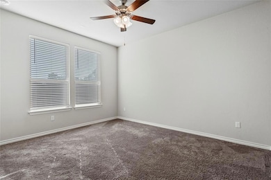 Spare room with ceiling fan, carpet, and baseboar